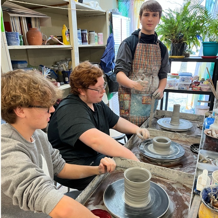 three students use the potters wheel